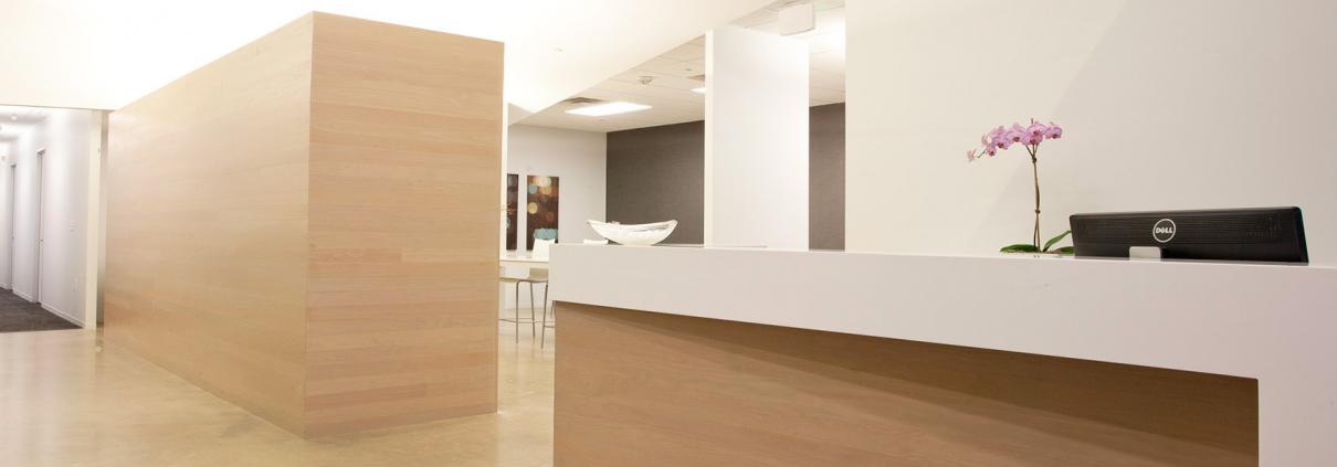 Renovated reception area with light wood veneer reception desk and wall feature