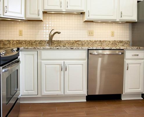 Senior living construction. Renovated kitchen with white cabinet and brown marble countertops