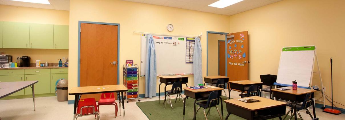 Classroom interior with desks, white board and play area